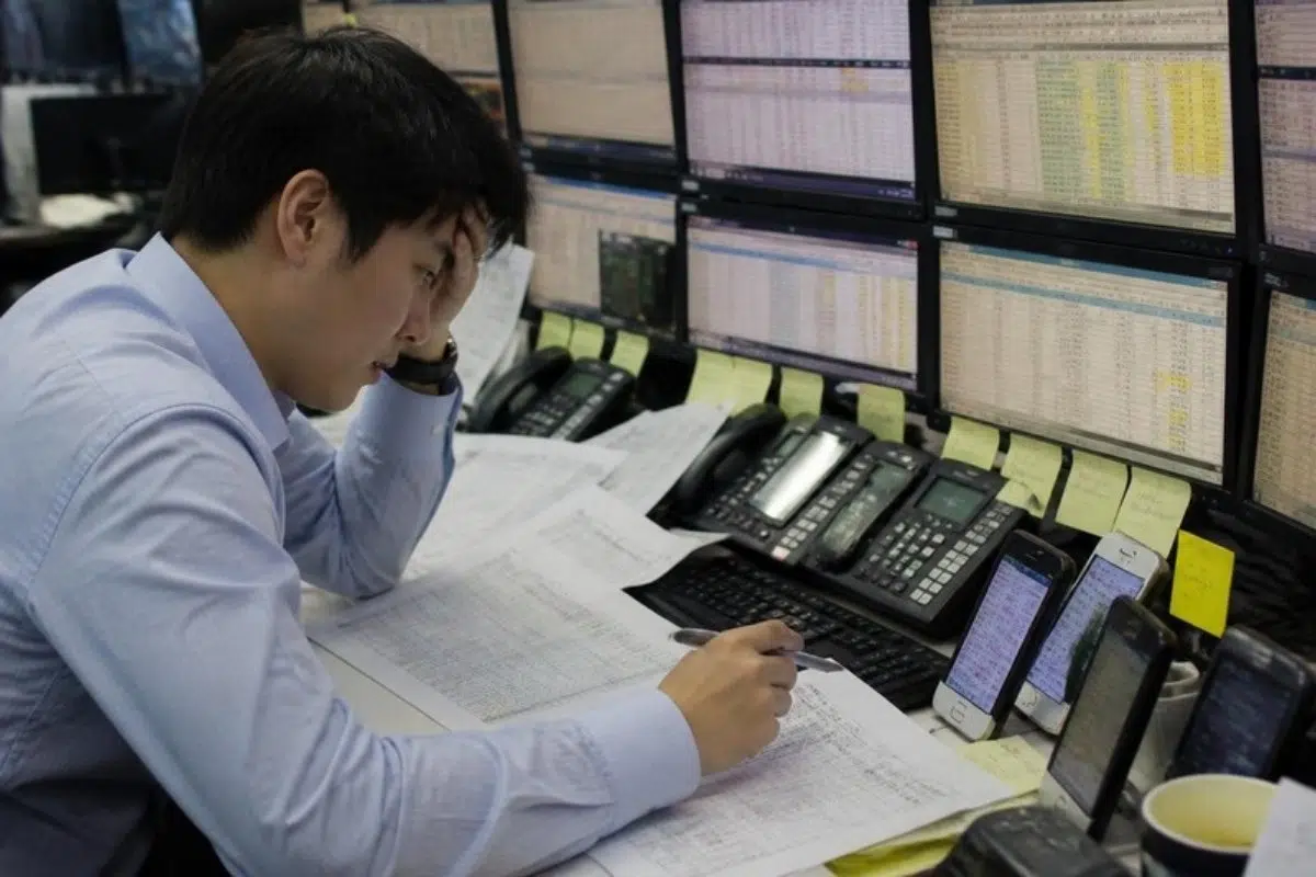 FX trader manually checking currency rates and printed trade confirmations
