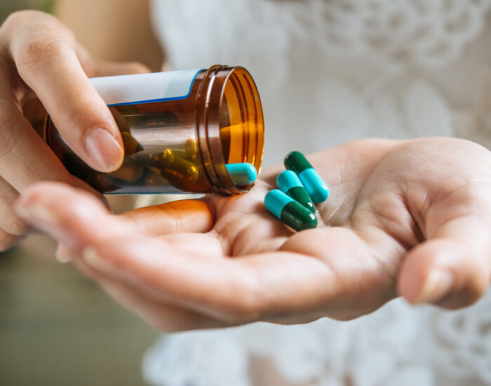 Woman's hand pours the medicine pills out of the bottle