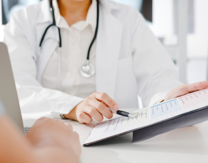 Young Asia female doctor in white medical uniform using clipboar